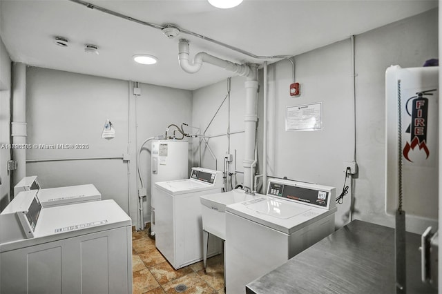 laundry area featuring washer and dryer, electric water heater, and sink