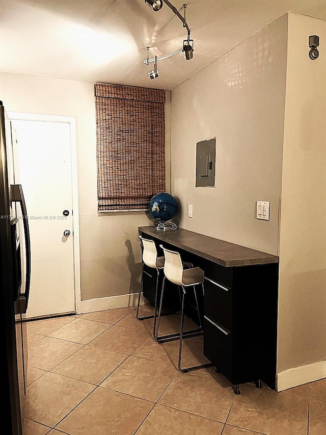 interior space featuring electric panel, light tile patterned flooring, and refrigerator