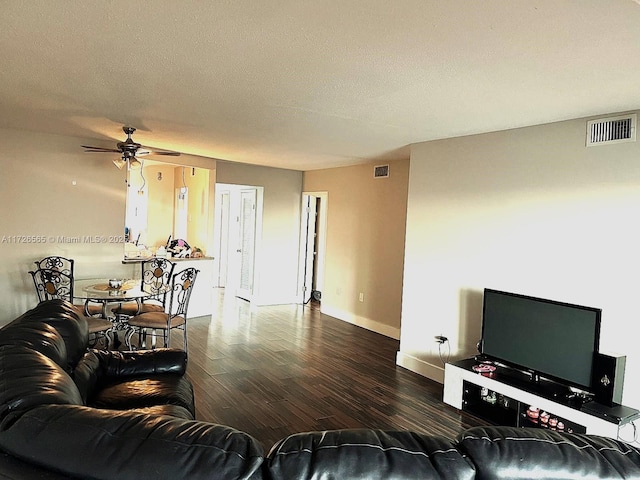 living room featuring a textured ceiling, ceiling fan, and dark hardwood / wood-style flooring