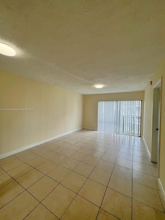 tiled spare room featuring a textured ceiling