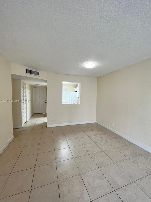 tiled empty room with a textured ceiling