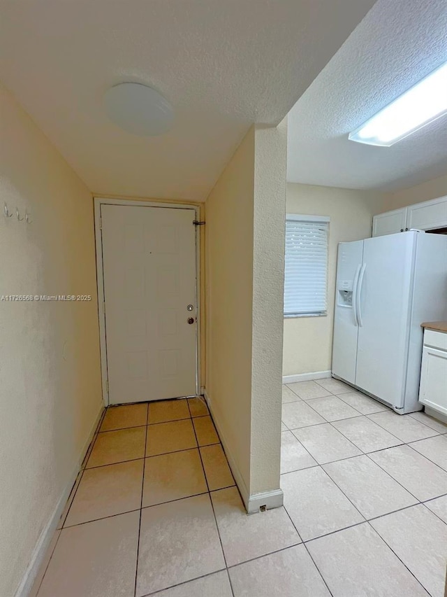 hallway with a textured ceiling and light tile patterned flooring