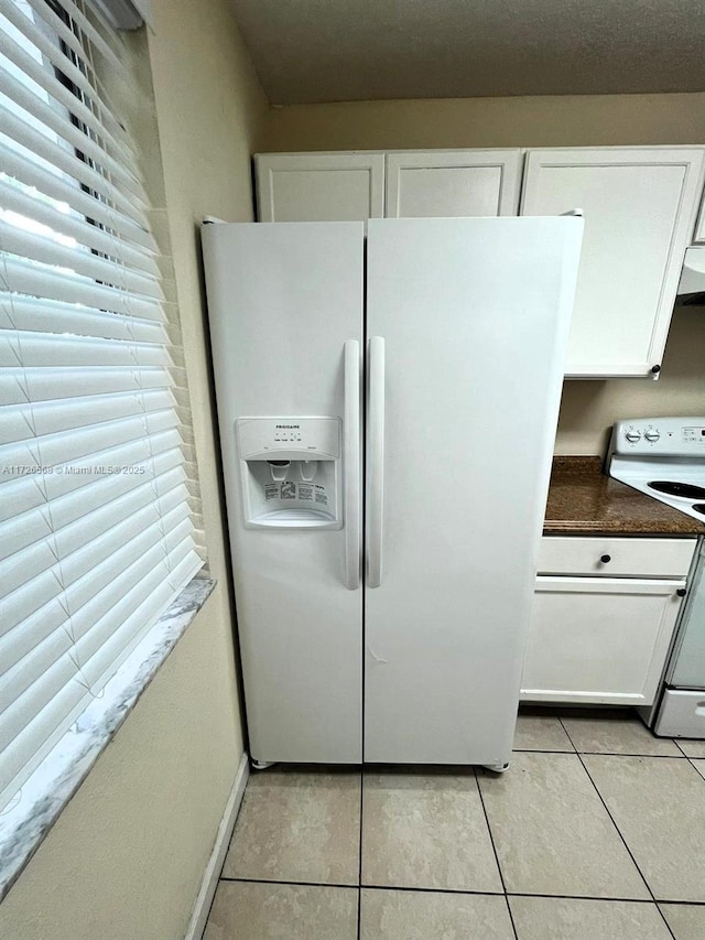 kitchen featuring light tile patterned floors, white appliances, and white cabinets