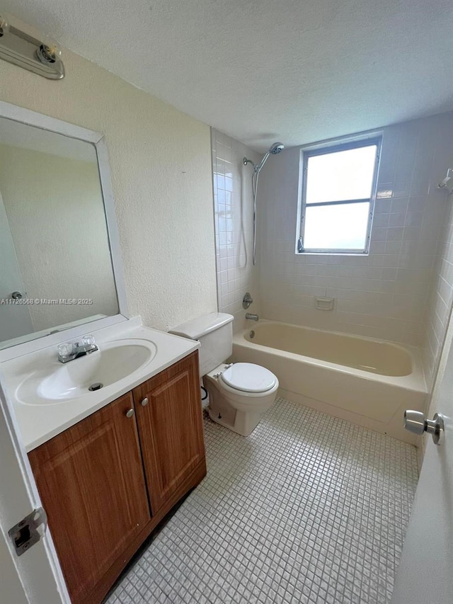 full bathroom with toilet, tile patterned flooring, tiled shower / bath, and vanity