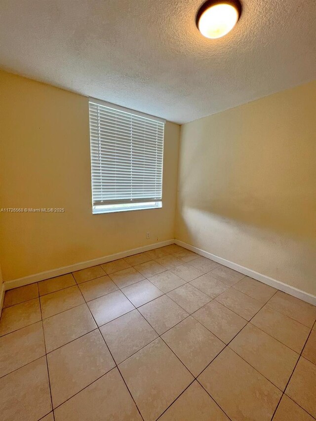 tiled spare room with a textured ceiling