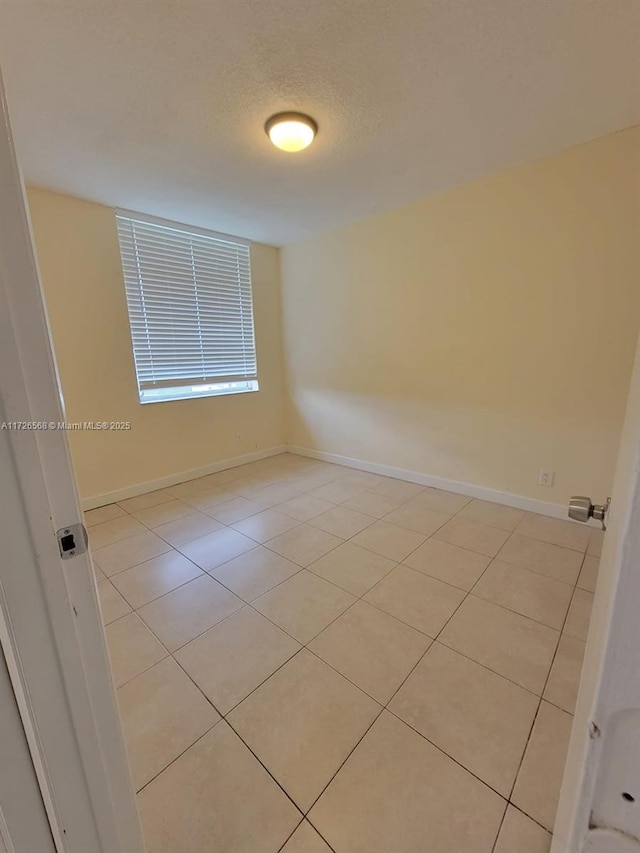 spare room with light tile patterned flooring and a textured ceiling