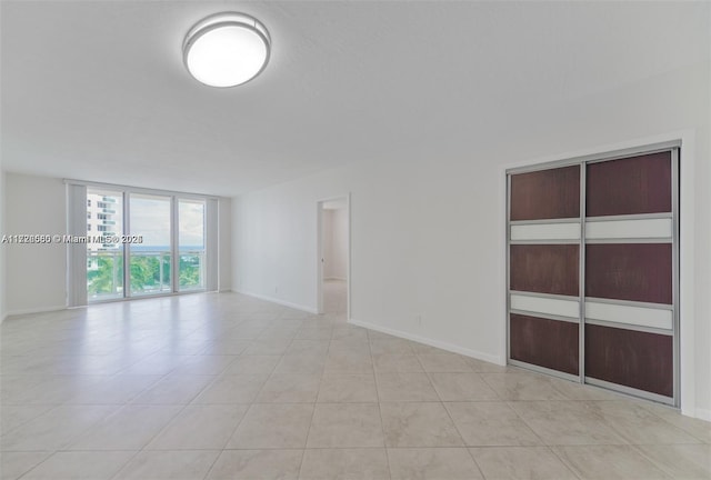 unfurnished room with light tile patterned floors and expansive windows