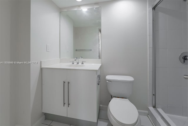 bathroom featuring toilet, a shower with door, vanity, and tile patterned flooring