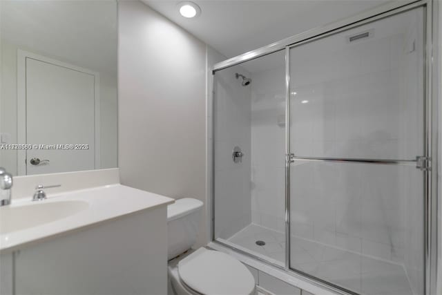 bathroom featuring toilet, a shower with door, and vanity