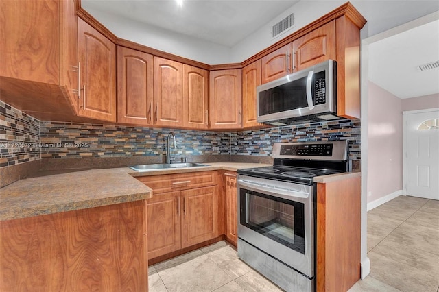 kitchen featuring sink, light tile patterned floors, backsplash, and appliances with stainless steel finishes