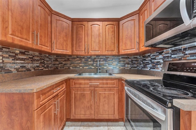 kitchen featuring appliances with stainless steel finishes, light tile patterned floors, decorative backsplash, and sink