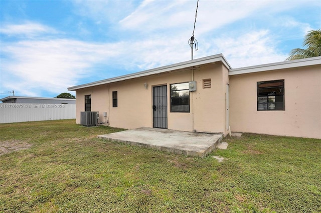 rear view of property with a lawn, a patio area, and central air condition unit