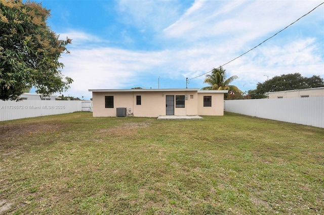 back of property with a yard and central AC