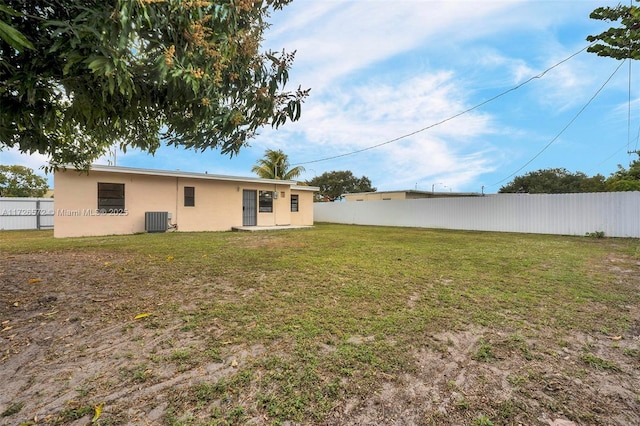 rear view of house featuring a lawn and central AC unit