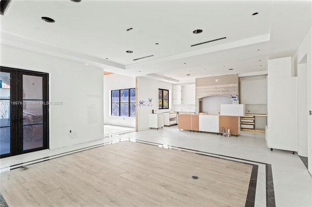 unfurnished living room with a raised ceiling, french doors, and recessed lighting