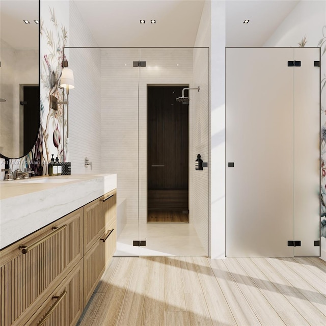 bathroom with walk in shower, vanity, and wood finished floors