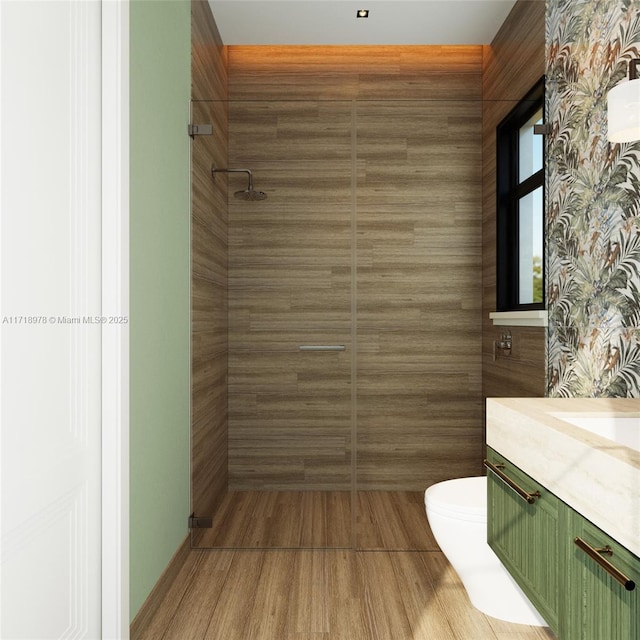 full bath featuring tiled shower, vanity, toilet, and wood finished floors