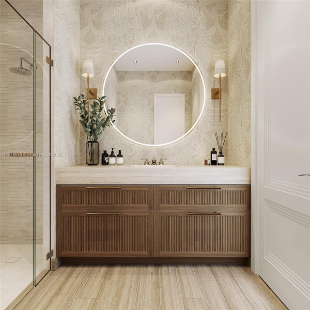 full bath with wallpapered walls, wood finished floors, a stall shower, and vanity