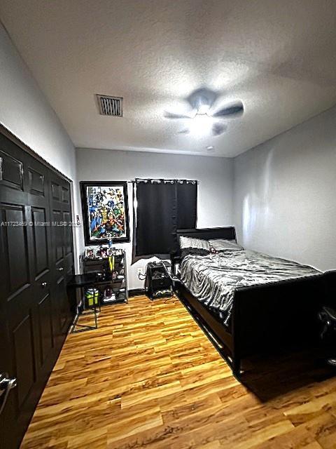 bedroom with wood-type flooring, a closet, ceiling fan, and a textured ceiling