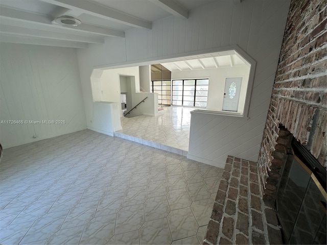 unfurnished living room featuring light tile patterned flooring, beamed ceiling, and a fireplace