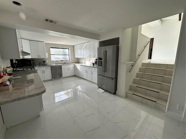 kitchen featuring sink, white cabinetry, backsplash, light stone countertops, and appliances with stainless steel finishes