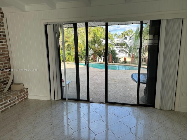 doorway featuring beam ceiling and light tile patterned floors