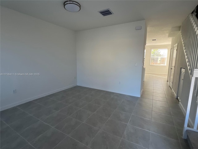 spare room featuring dark tile patterned flooring