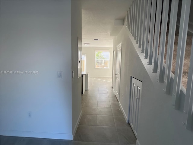 corridor featuring tile patterned flooring and a textured ceiling