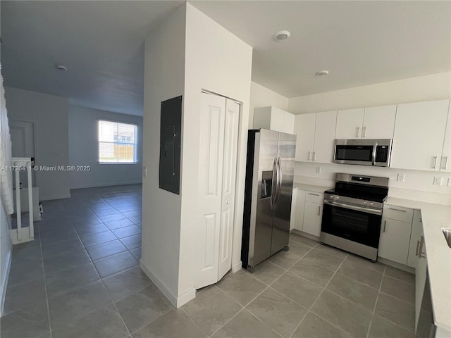 kitchen with light tile patterned floors, electric panel, white cabinets, and appliances with stainless steel finishes