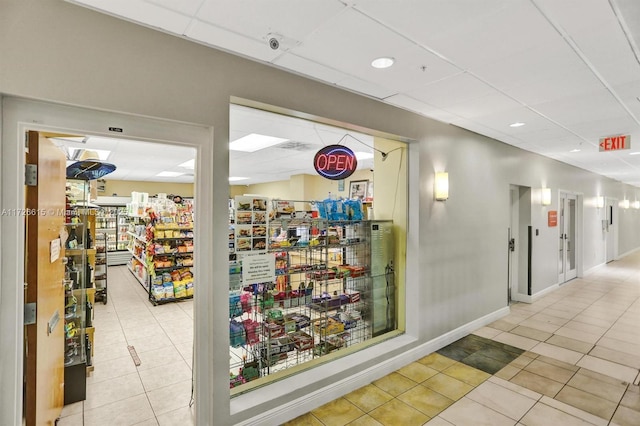 hall with a drop ceiling and light tile patterned floors