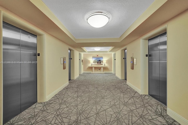 hallway with a textured ceiling and elevator