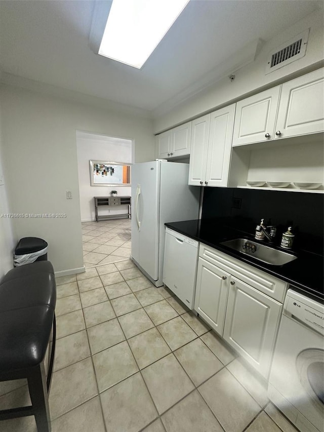 kitchen with sink, white cabinets, washer / dryer, and ornamental molding