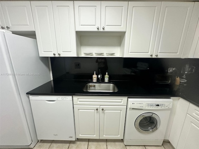 kitchen featuring white appliances, washer / dryer, white cabinets, and sink