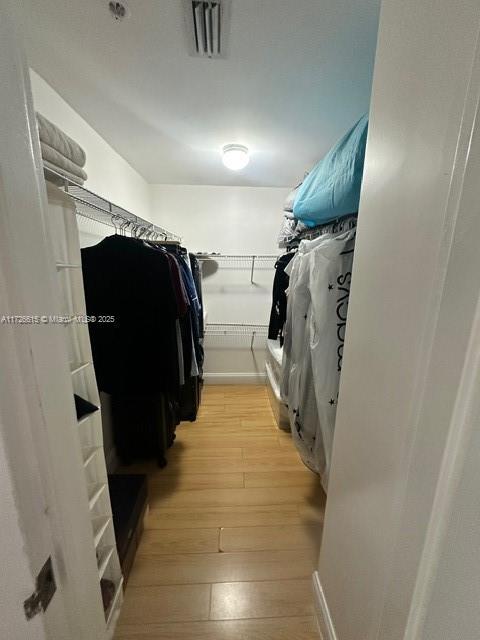 walk in closet with light hardwood / wood-style floors