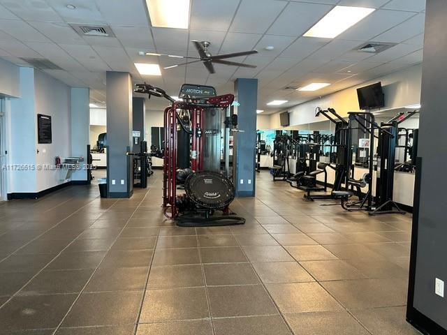 exercise room with a drop ceiling and ceiling fan