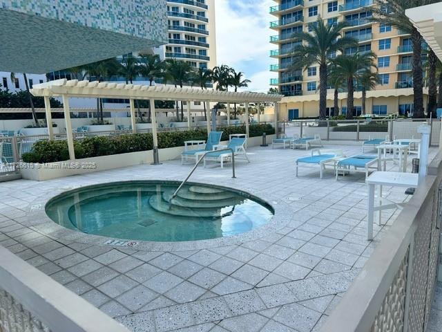 view of swimming pool featuring a community hot tub, a patio area, and a pergola