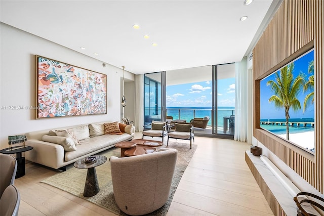 living room with a wall of windows, light hardwood / wood-style flooring, and a water view