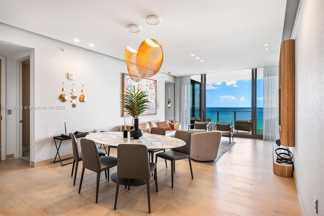 dining room with light hardwood / wood-style floors, floor to ceiling windows, and a water view