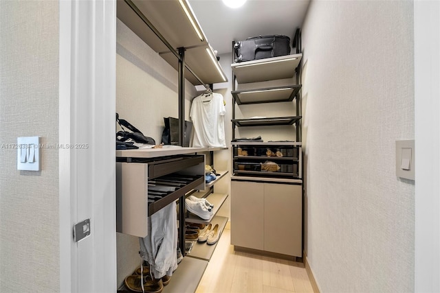 walk in closet with light hardwood / wood-style floors