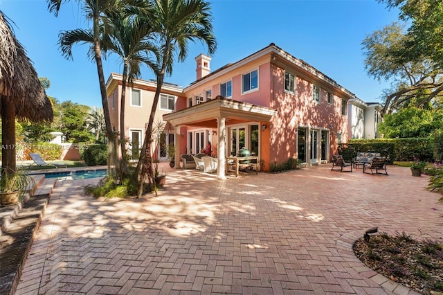 rear view of house with a fenced in pool, french doors, and a patio