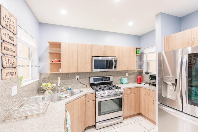 kitchen featuring appliances with stainless steel finishes, light tile patterned floors, decorative backsplash, light brown cabinets, and sink