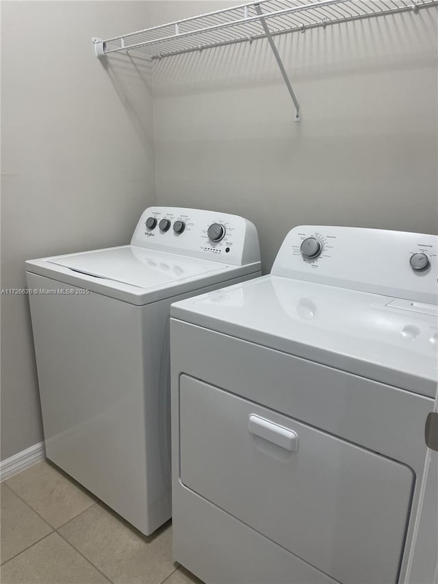 laundry area featuring light tile patterned floors, washing machine and dryer, laundry area, and baseboards