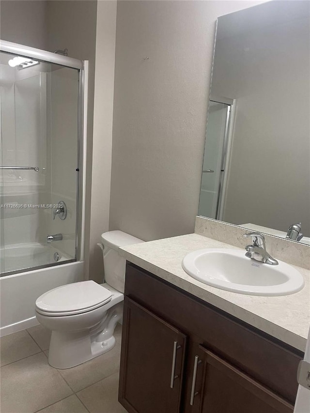full bath with tile patterned flooring, enclosed tub / shower combo, vanity, and toilet