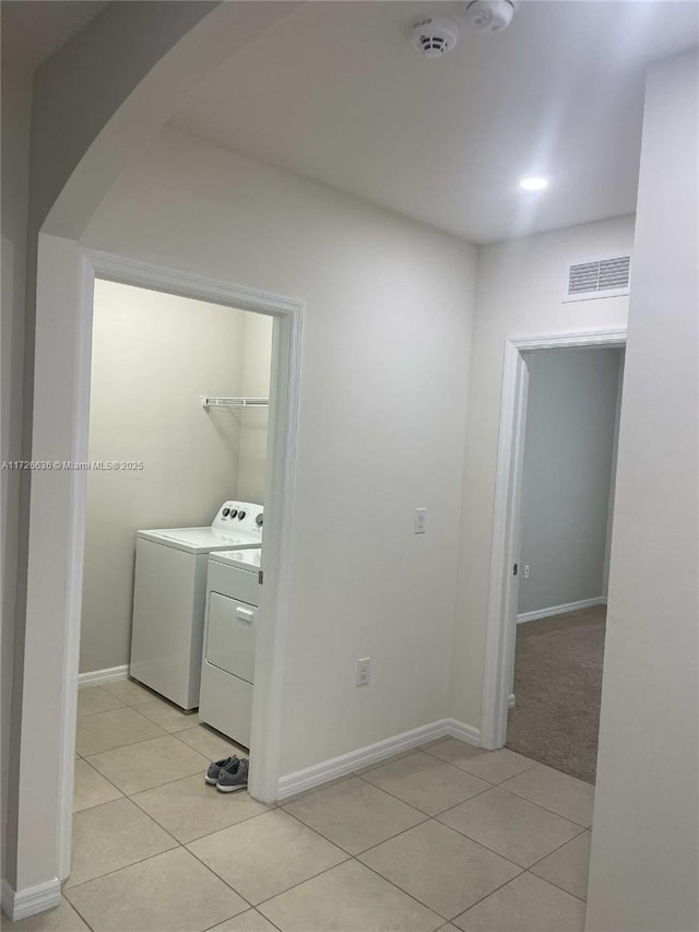clothes washing area with laundry area, light tile patterned floors, arched walkways, visible vents, and baseboards