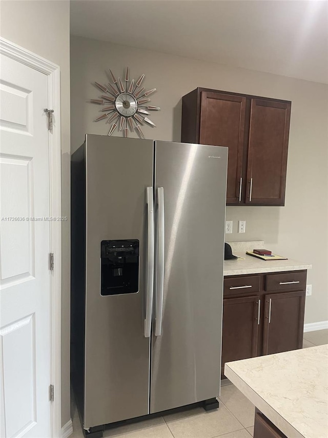 kitchen featuring stainless steel refrigerator with ice dispenser, dark brown cabinetry, and light countertops