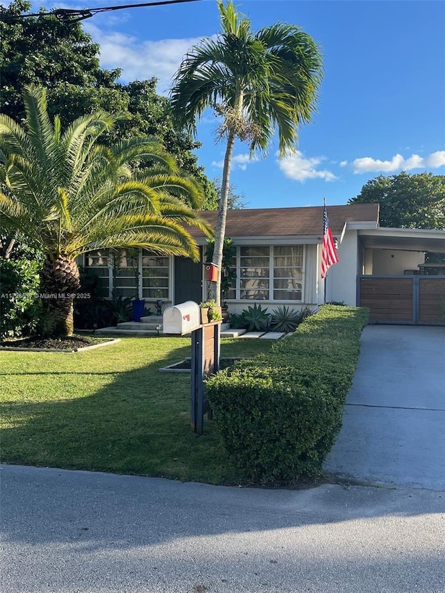 view of front of property with a front lawn, a carport, and driveway