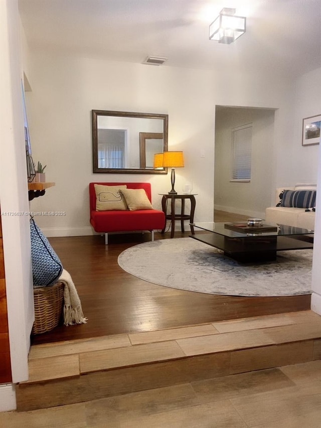 living area with visible vents, baseboards, and wood finished floors