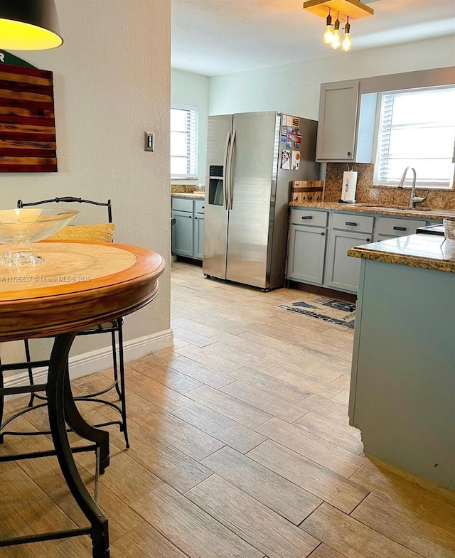 kitchen with tasteful backsplash, stainless steel fridge with ice dispenser, gray cabinets, and light wood finished floors