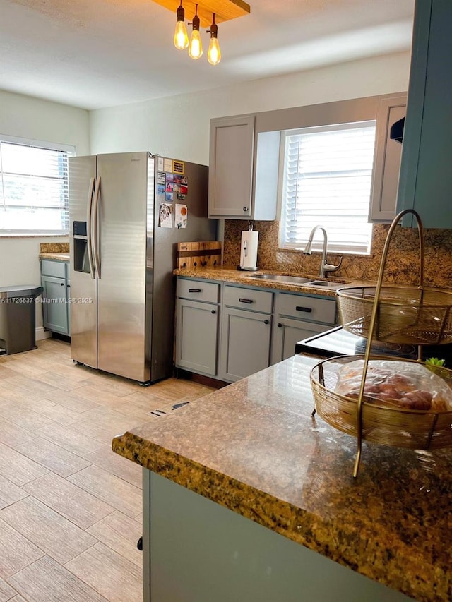 kitchen featuring a sink, tasteful backsplash, gray cabinets, and stainless steel refrigerator with ice dispenser