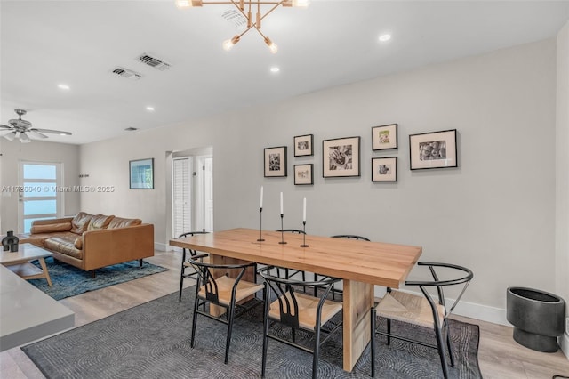 dining room with hardwood / wood-style flooring and ceiling fan with notable chandelier